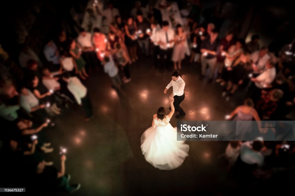 Top view on a wedding couple dancing the opening waltz at their wedding celebration. All their friends are standing in a ring around them with a light in their hands. Focus only on the bridal couple.